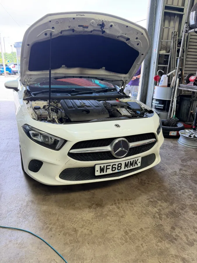 White Ford with its bonnet open in a workshop