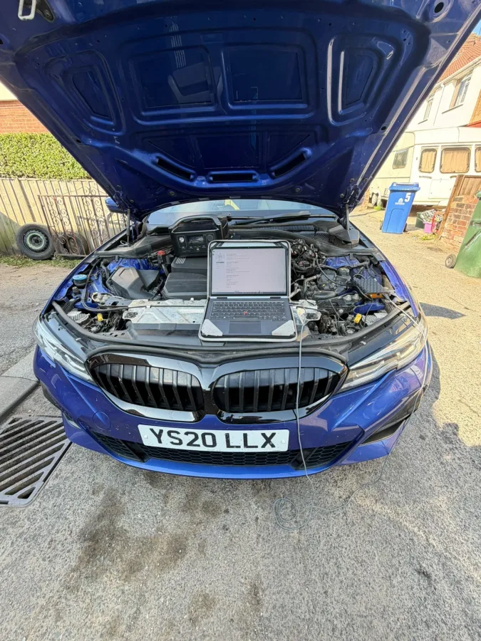 BMW with its bonnet open and laptop in the engine bay